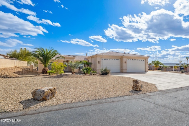 view of front of house with concrete driveway, an attached garage, fence, and stucco siding