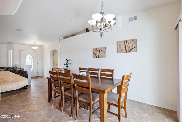 dining space with baseboards, visible vents, arched walkways, tile patterned floors, and a chandelier