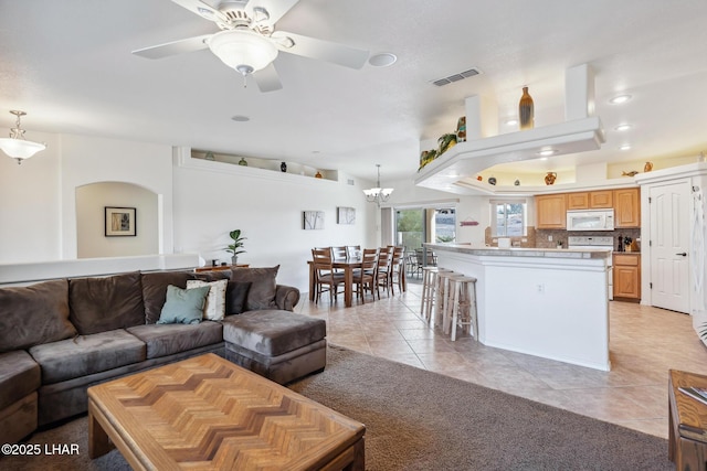 living room featuring light tile patterned floors, ceiling fan with notable chandelier, visible vents, and recessed lighting