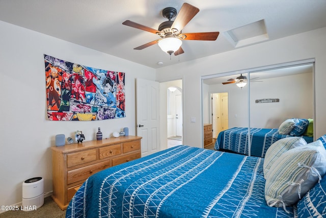 bedroom with carpet, attic access, and a ceiling fan