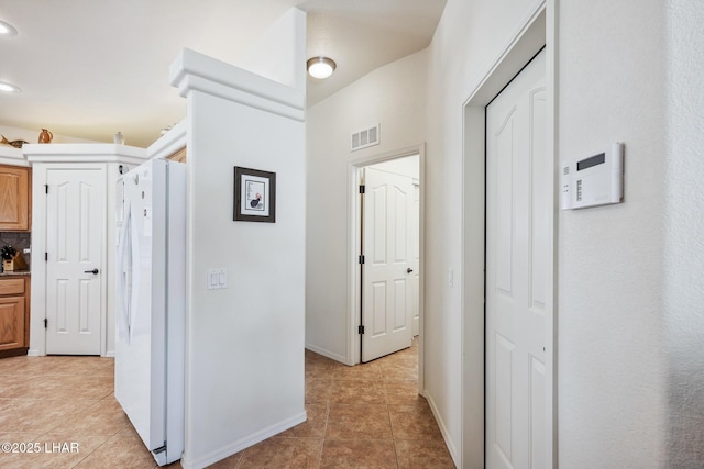 corridor featuring light tile patterned floors, visible vents, and baseboards