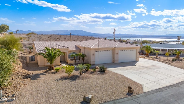 view of front facade featuring a garage, concrete driveway, a tiled roof, a mountain view, and stucco siding