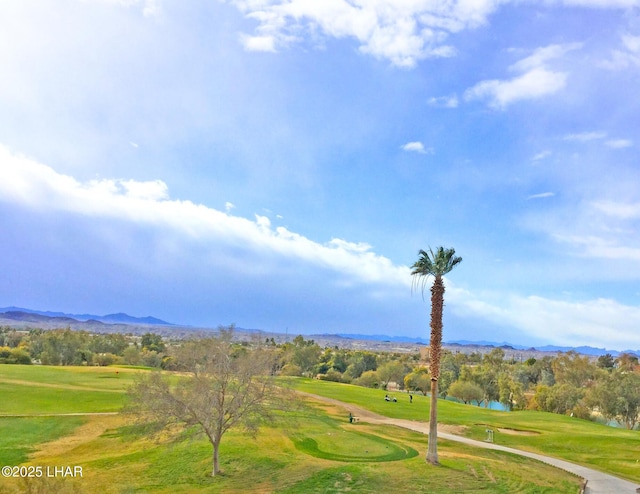 view of property's community featuring view of golf course, a lawn, and a mountain view