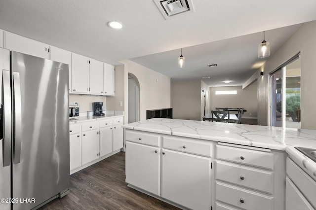 kitchen featuring stainless steel fridge, arched walkways, white cabinets, and dark wood-style flooring