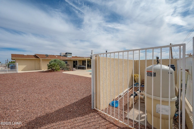 view of gate with a fenced backyard and a patio