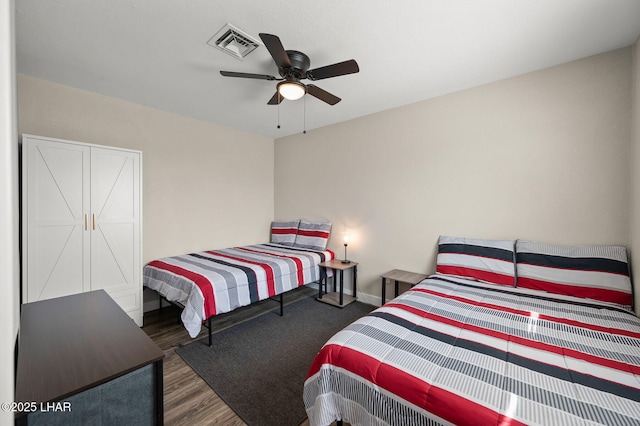 bedroom featuring ceiling fan, baseboards, visible vents, and wood finished floors