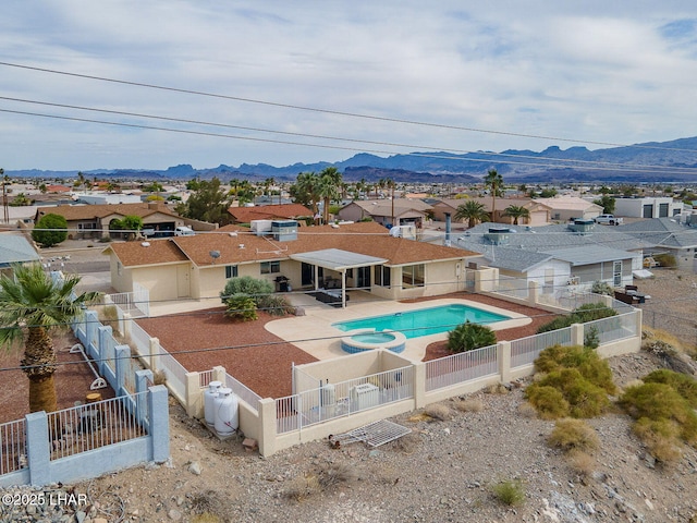 view of swimming pool with a fenced backyard, a mountain view, a pool with connected hot tub, and a residential view