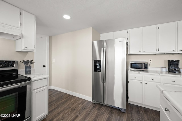 kitchen with appliances with stainless steel finishes, range hood, dark wood finished floors, baseboards, and white cabinets