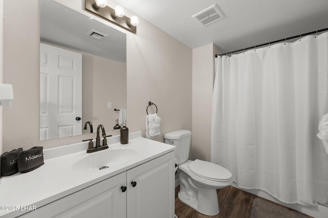bathroom with vanity, toilet, wood finished floors, and visible vents