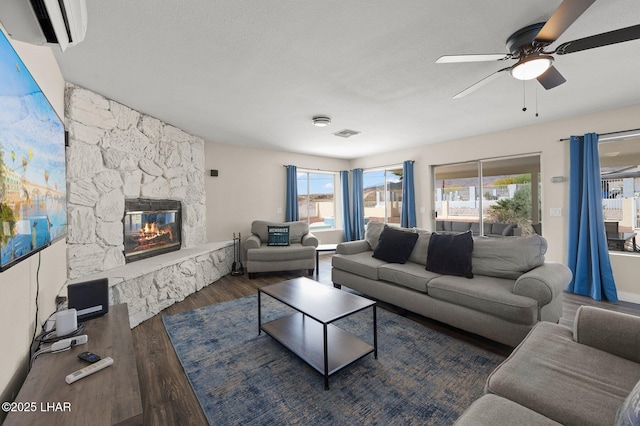 living area featuring a fireplace, a ceiling fan, wood finished floors, and visible vents
