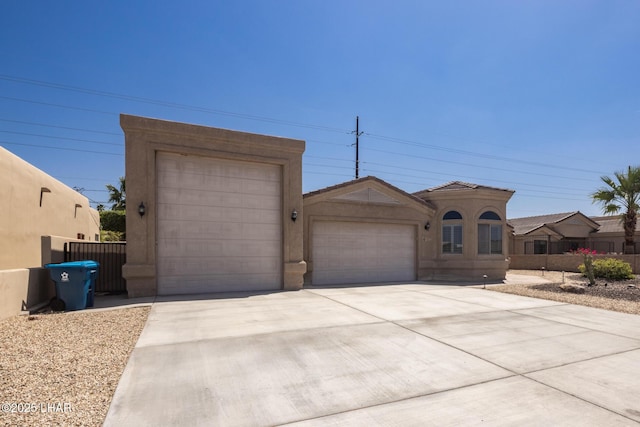 view of front of property featuring a tile roof, driveway, fence, a garage, and stucco siding