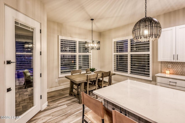 dining space featuring a chandelier, light wood-style flooring, and baseboards