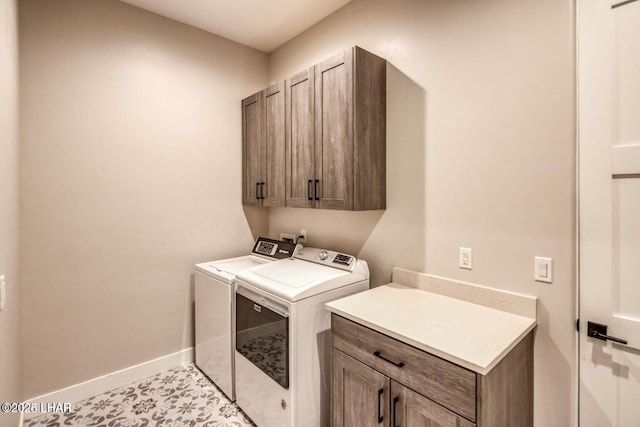 washroom featuring separate washer and dryer, cabinet space, and baseboards