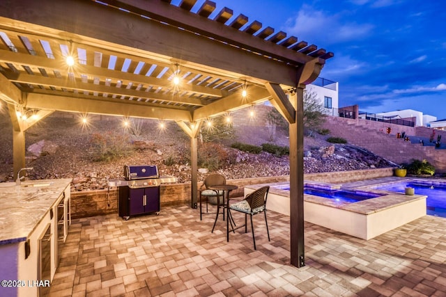 view of patio featuring an outdoor kitchen, a pergola, a sink, an in ground hot tub, and a fenced backyard