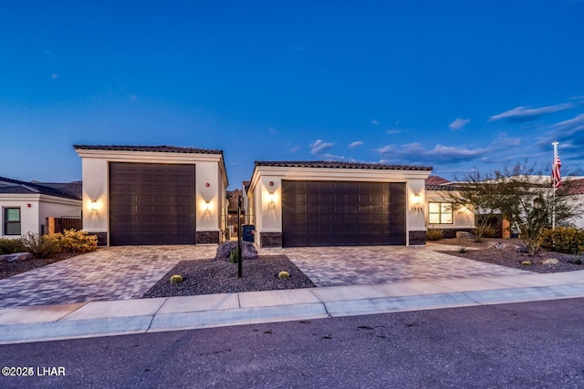 view of front of property featuring stone siding, decorative driveway, and stucco siding