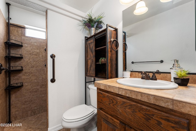 bathroom with vanity, toilet, and a tile shower