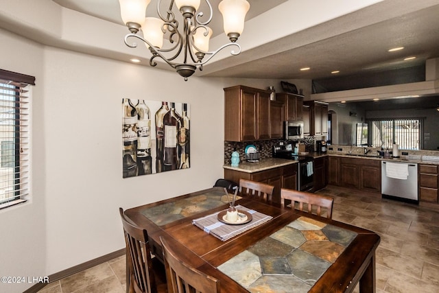 dining room with sink, a wealth of natural light, and a chandelier