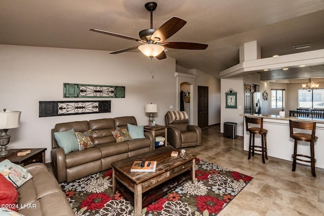 living room with lofted ceiling and ceiling fan with notable chandelier