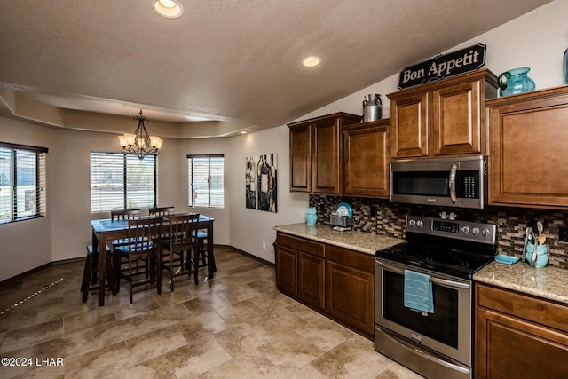 kitchen featuring a notable chandelier, stainless steel appliances, decorative backsplash, and a wealth of natural light