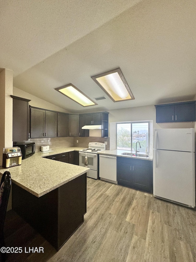 kitchen featuring light wood-style floors, a sink, white appliances, a peninsula, and under cabinet range hood