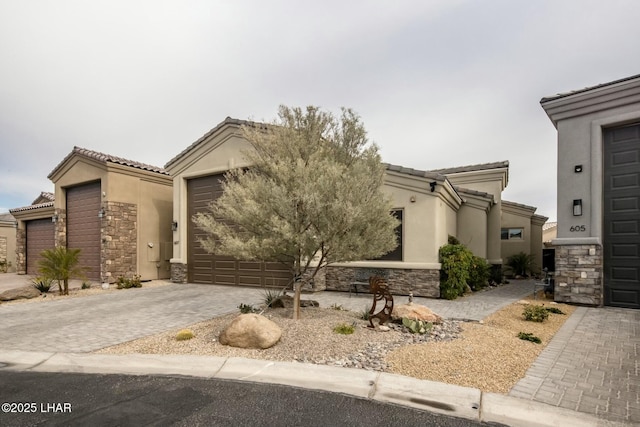 view of front of property featuring stucco siding, a tile roof, decorative driveway, stone siding, and an attached garage