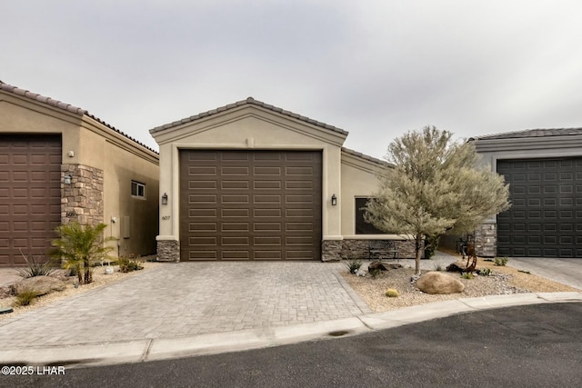 view of front of home featuring a tiled roof, decorative driveway, stone siding, and stucco siding