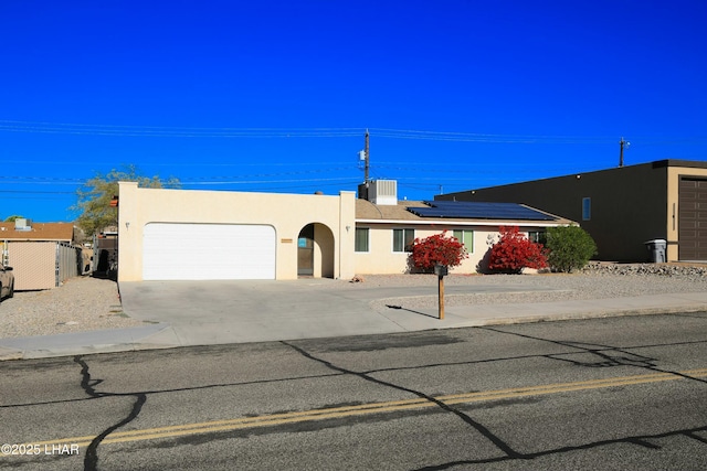 view of front of house with a garage, central AC, and solar panels