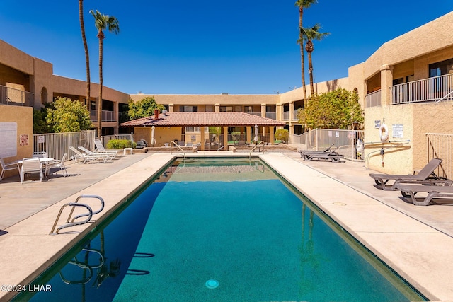 pool with a patio area and fence