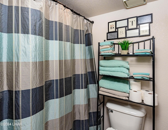 bathroom with walk in shower, a wall mounted air conditioner, toilet, and a textured ceiling