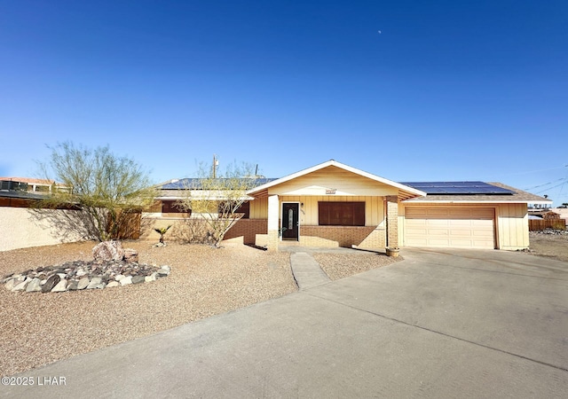 ranch-style home featuring a garage and solar panels