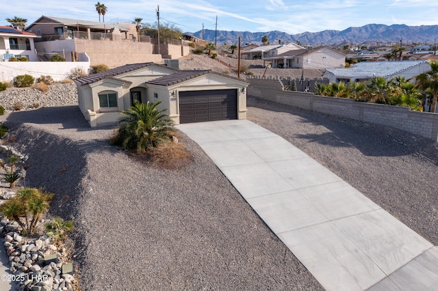 view of front facade with an attached garage, a mountain view, driveway, a residential view, and stucco siding