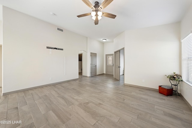 empty room with a ceiling fan, light wood-type flooring, visible vents, and baseboards