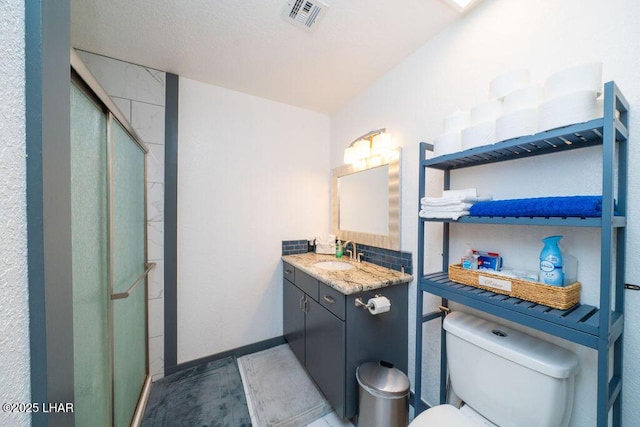 full bath with visible vents, toilet, a shower stall, vanity, and baseboards