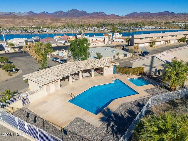 community pool with fence, a water and mountain view, and a patio