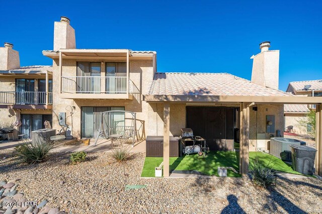 rear view of house with stucco siding, a patio area, a balcony, and central air condition unit