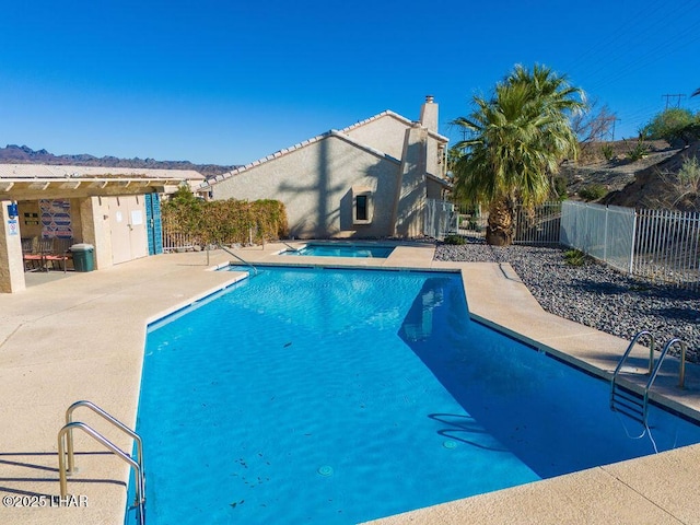 pool with a patio, fence, and a hot tub