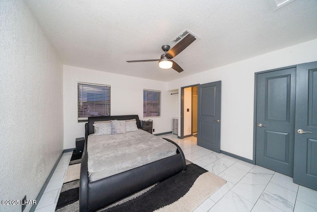 bedroom with a textured ceiling, marble finish floor, visible vents, and baseboards