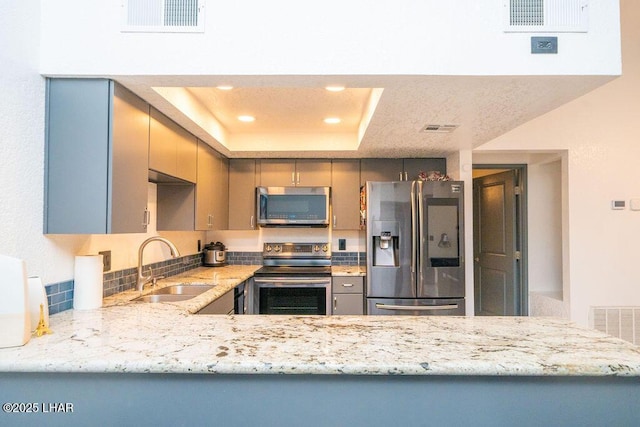 kitchen with a sink, appliances with stainless steel finishes, a raised ceiling, and visible vents