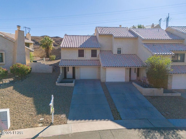 view of front facade with concrete driveway, a tiled roof, an attached garage, and stucco siding