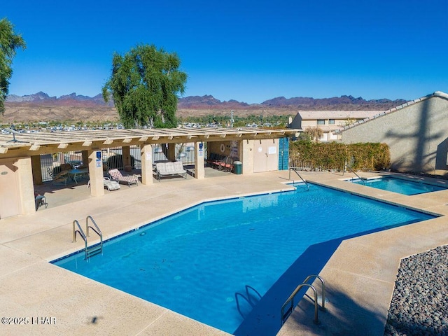 community pool with a community hot tub, a patio area, fence, and a mountain view