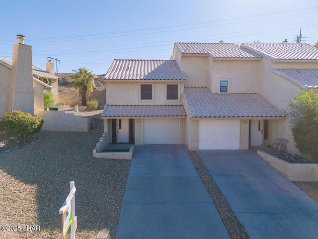 mediterranean / spanish-style home with an attached garage, stucco siding, concrete driveway, and a tiled roof