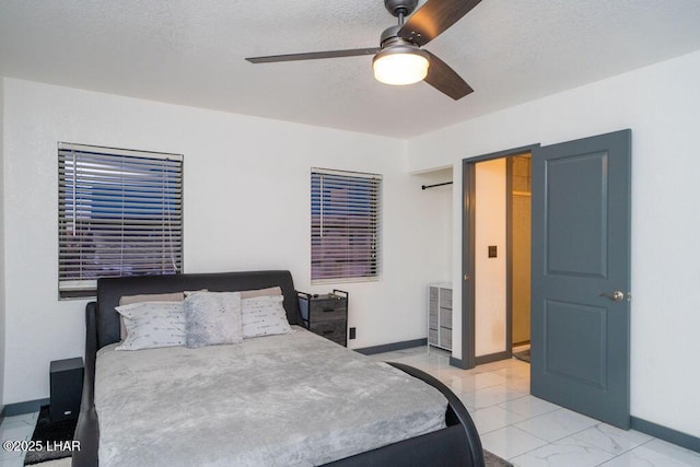 bedroom with a ceiling fan, marble finish floor, a textured ceiling, and baseboards