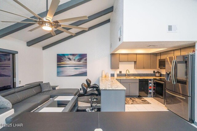 kitchen featuring visible vents, appliances with stainless steel finishes, beamed ceiling, a peninsula, and a sink