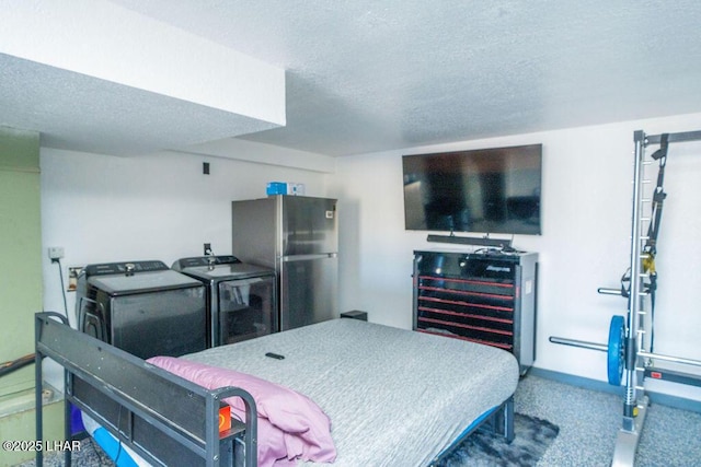 bedroom featuring beverage cooler, baseboards, freestanding refrigerator, a textured ceiling, and washing machine and dryer