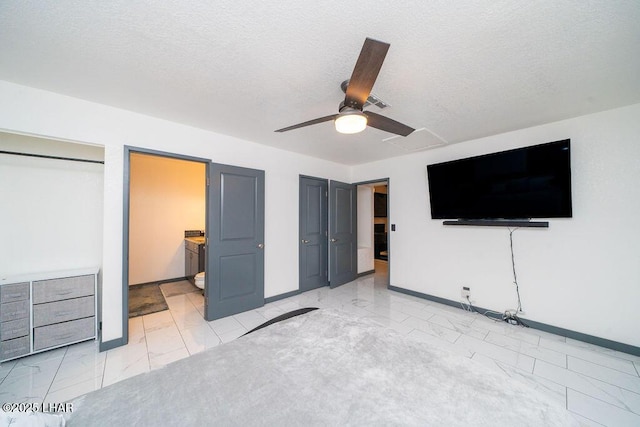 unfurnished bedroom featuring marble finish floor, ensuite bath, a textured ceiling, and baseboards