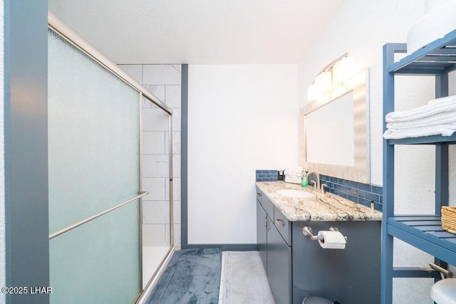 bathroom featuring baseboards, a shower stall, and vanity