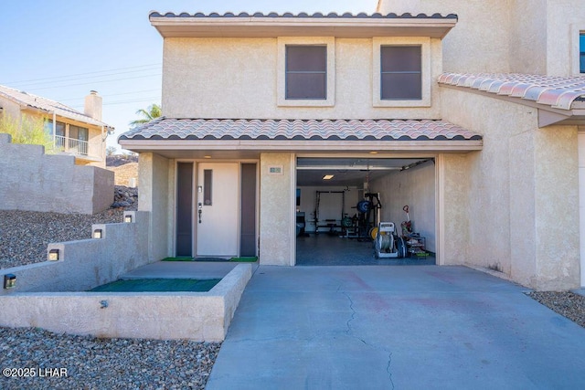 view of front of property with a garage, a tile roof, and stucco siding