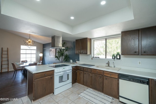 kitchen with light countertops, a sink, ventilation hood, white appliances, and a peninsula