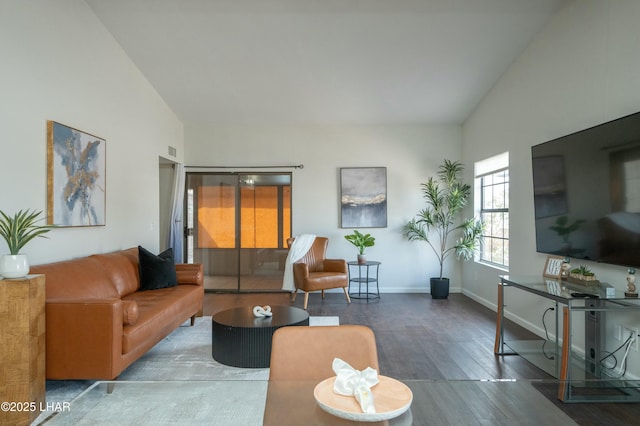 living area featuring high vaulted ceiling, wood finished floors, and baseboards