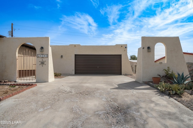 exterior space with a garage, driveway, a fenced front yard, and stucco siding